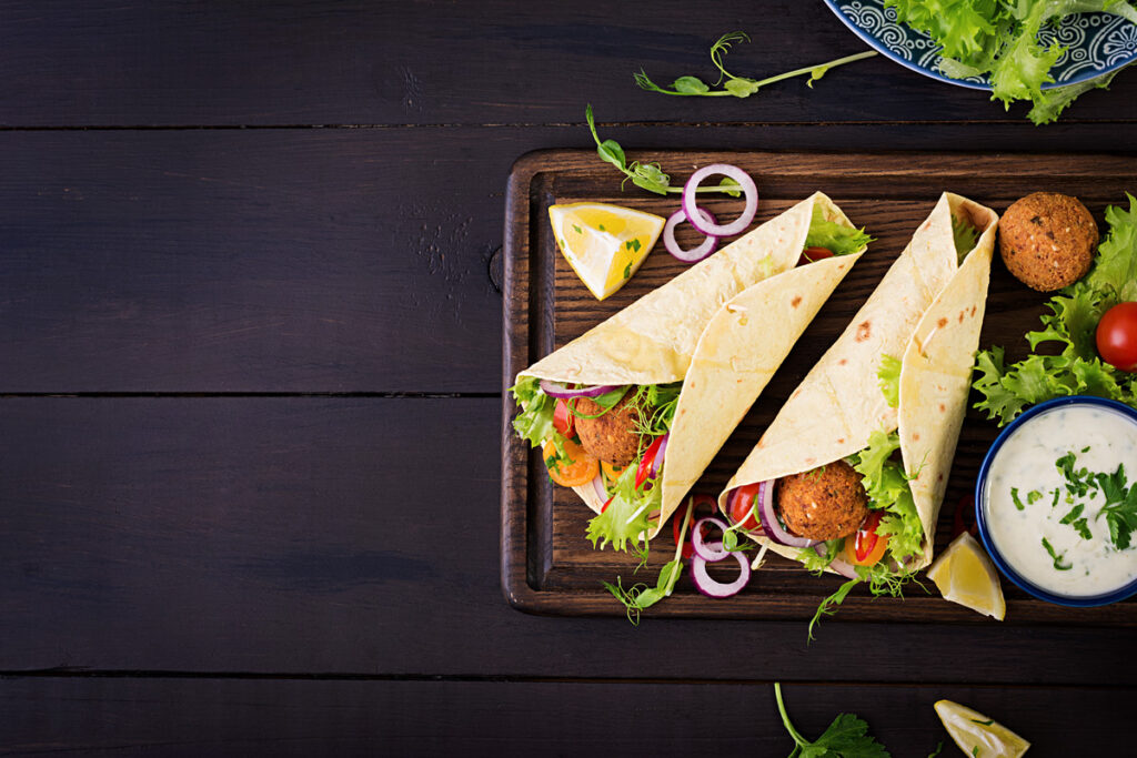Una envoltura de falafel: pan de pita, bolas de falafel, tomates, pepinos cortados en cubitos, cebollas y salsa