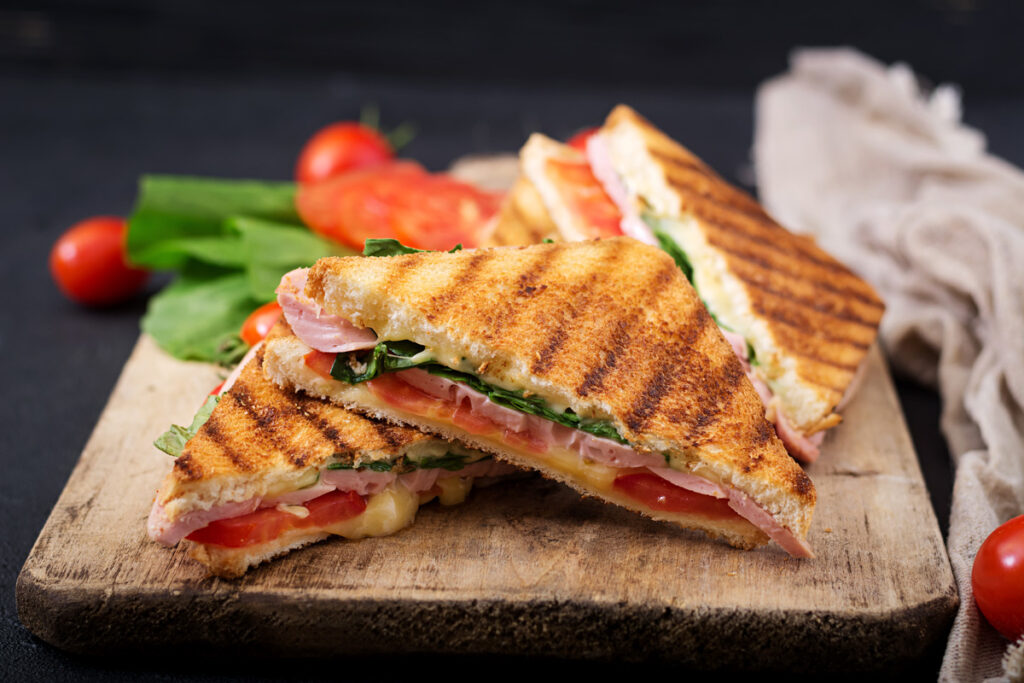 Sándwiches tostados de jamón, queso, tomate y hojas de lechuga.