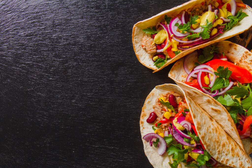 Un taco mexicano tradicional: una pequeña tortilla de maíz o trigo cubierta con carne, frijoles y verduras.
